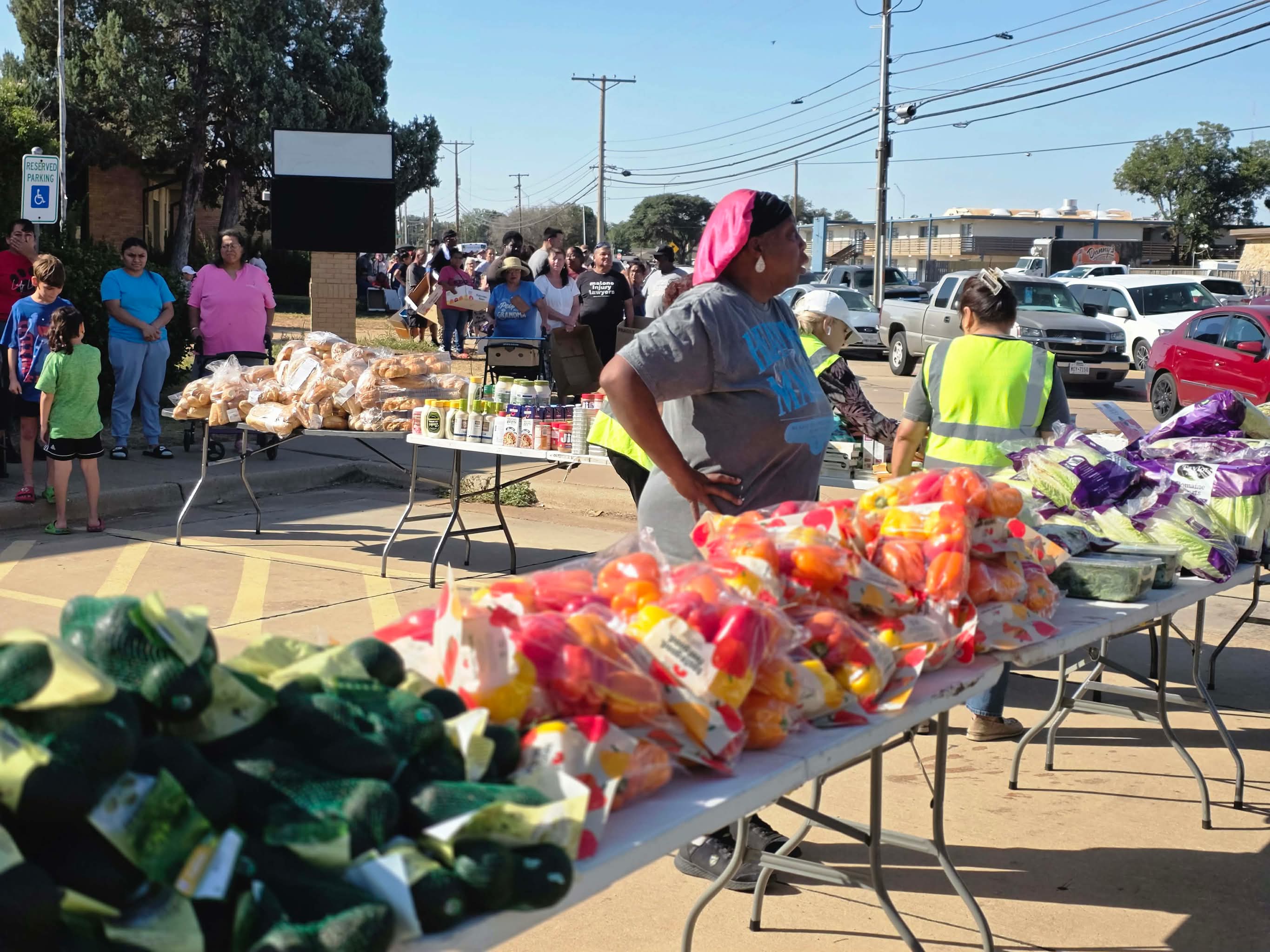 Volunteers and community members at the Heaven's Mana food distribution, tables of bread and fresh produce